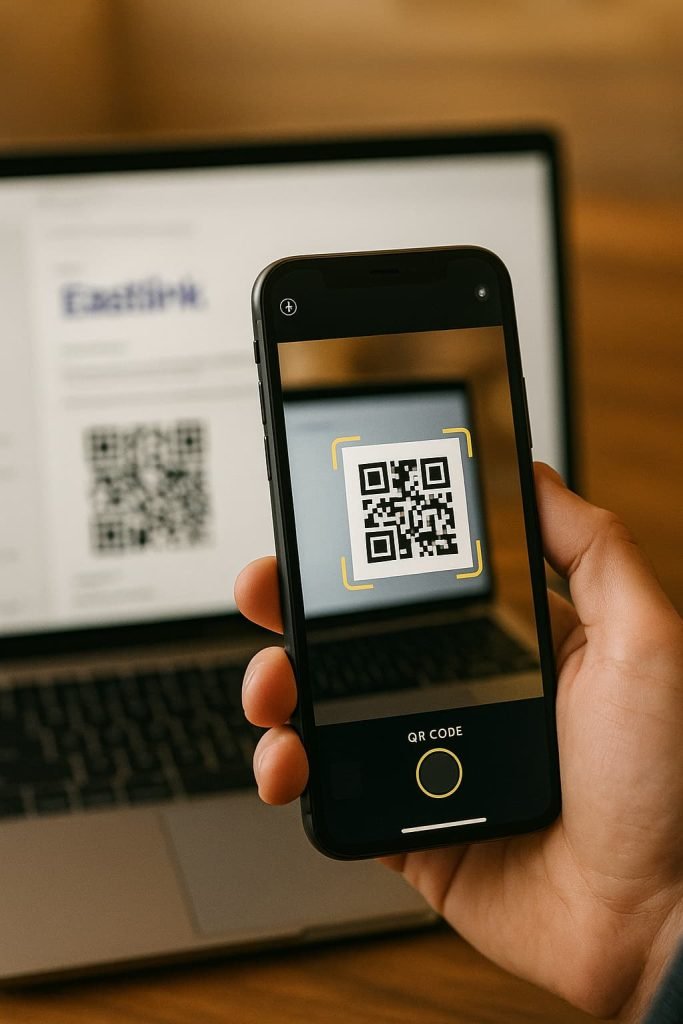 A person holding an iPhone and scanning a QR code to activate Eastlink eSIM in Canada, with the code displayed on a laptop screen in the background.